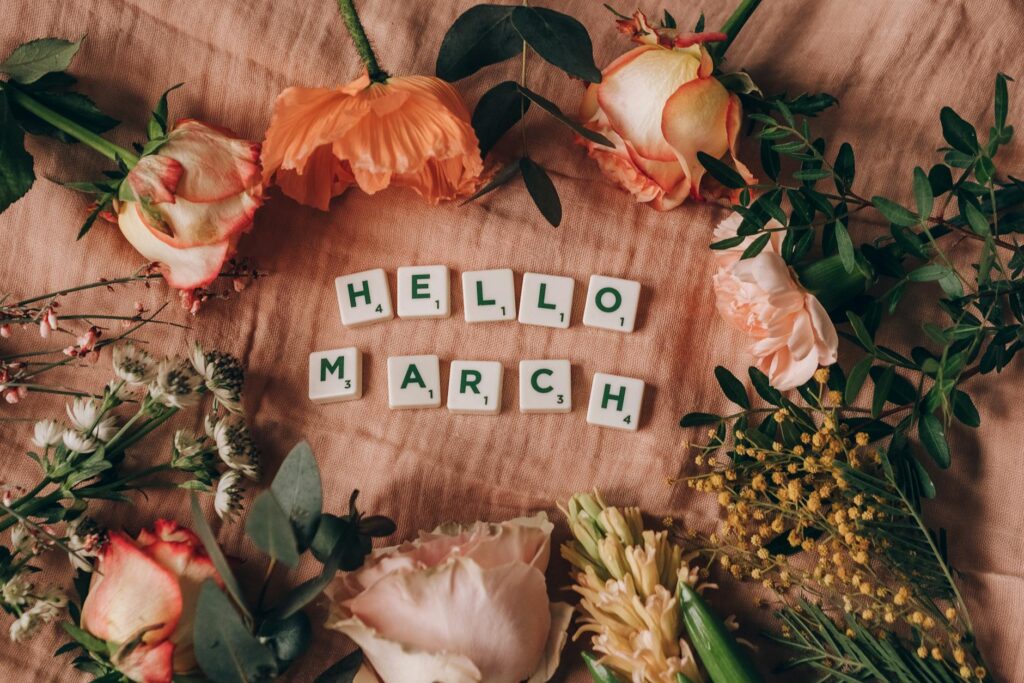 scrabble tiles on pink surface near flowers